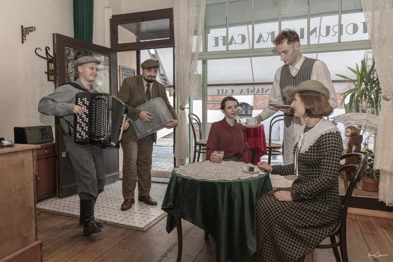 Goście w strojach z epoki i muzycy we wnętrzu Torunianka Cafe